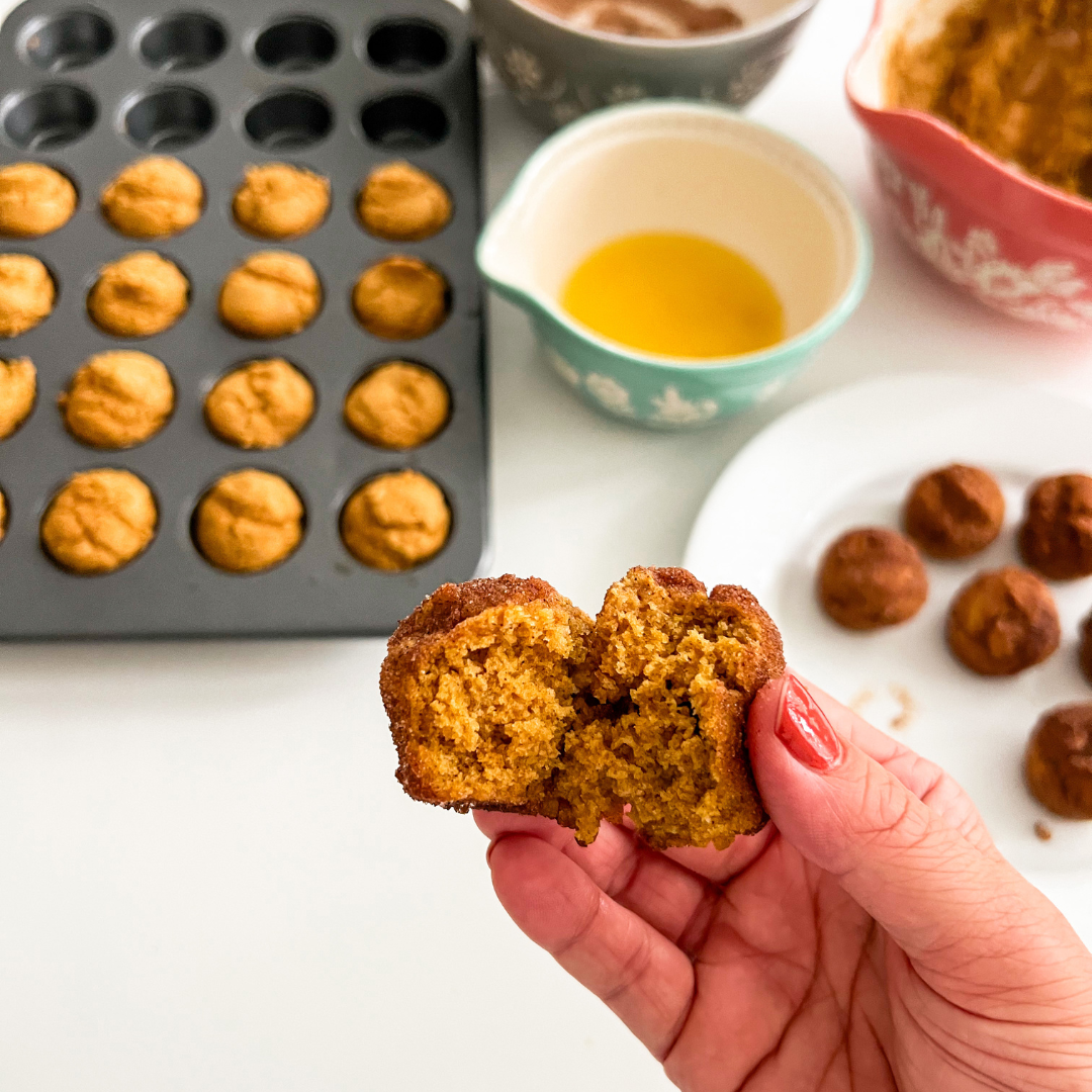 A hand holding an easy baked pumpkin donut hole
