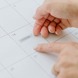 Hands placing a sticker on a day in the large wall calendar