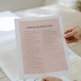 Hand holding a pink seasonal bucket list page from the family wall calendar