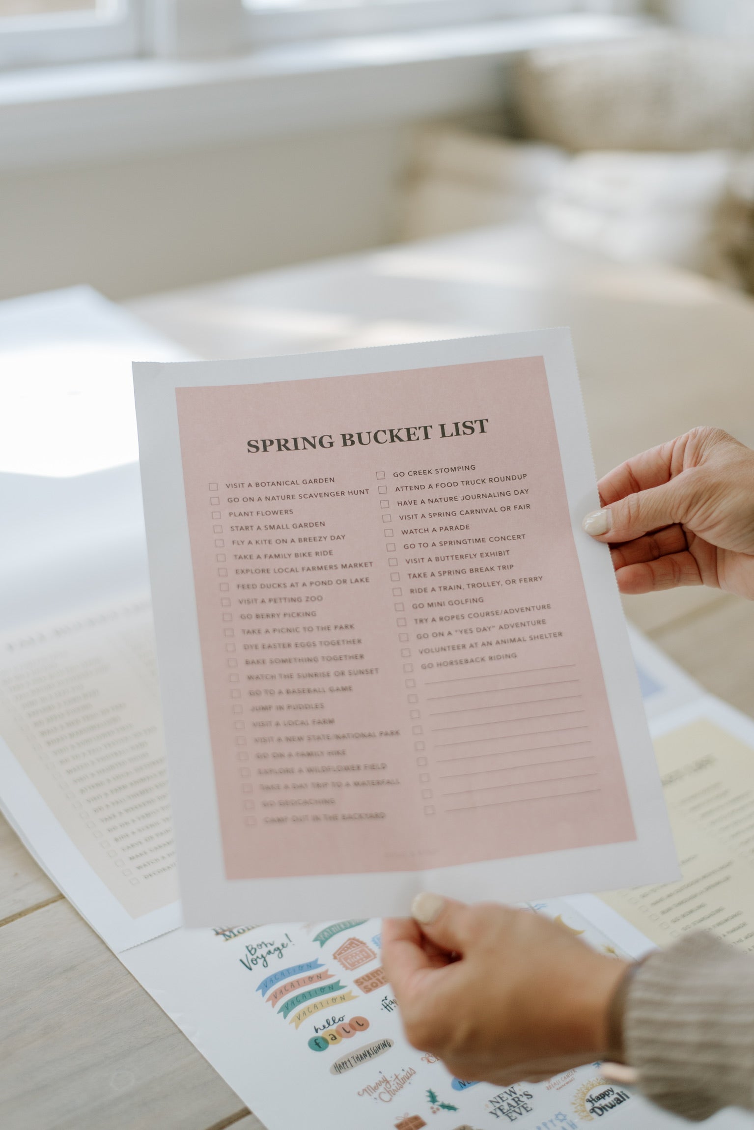 Hand holding a pink seasonal bucket list page from the family wall calendar