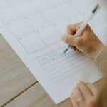 Hand writing in the notes section at the bottom of a monthly calendar page