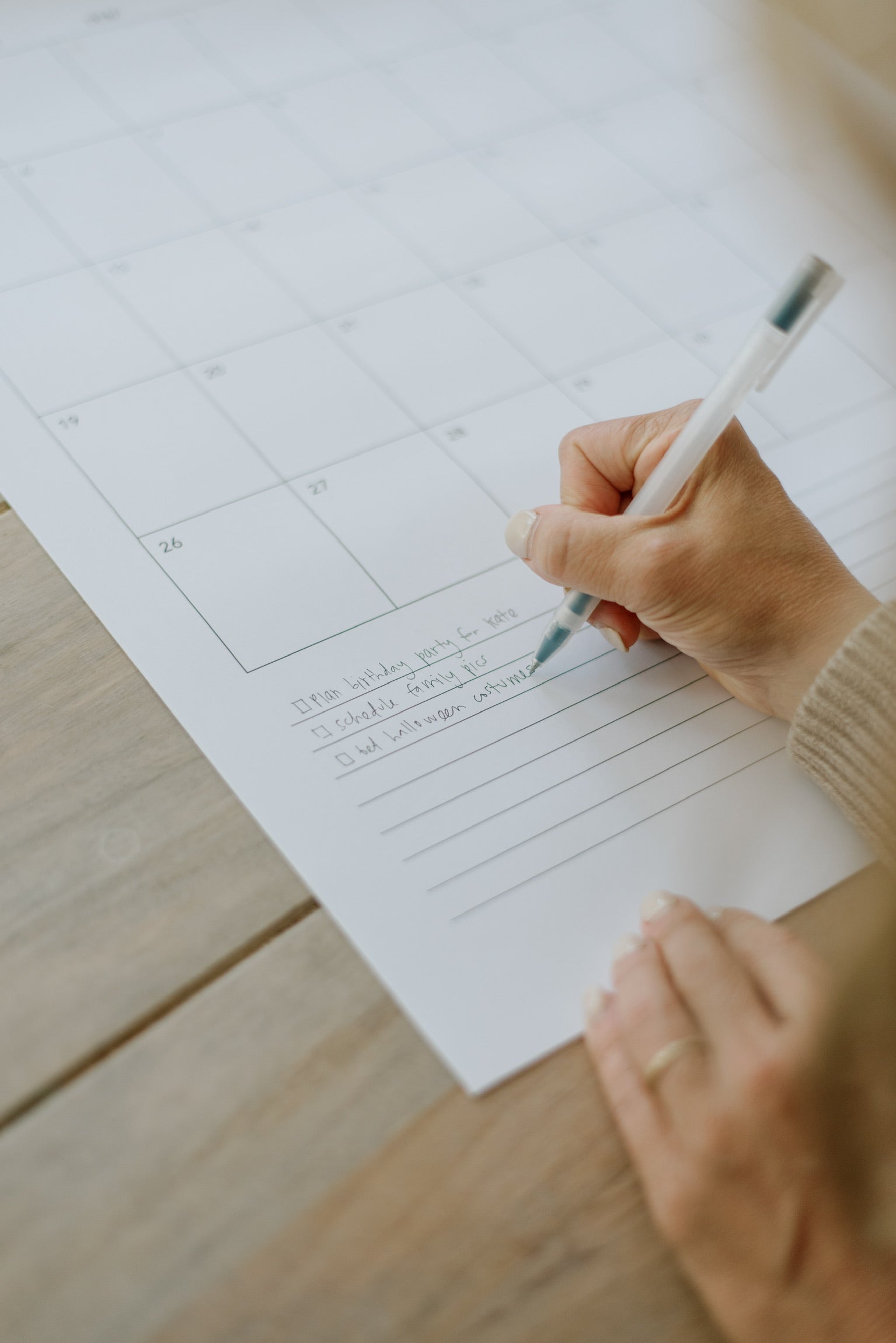 Hand writing in the notes section at the bottom of a monthly calendar page