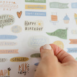 Hand peeling a happy birthday sticker from the family calendar sticker sheet
