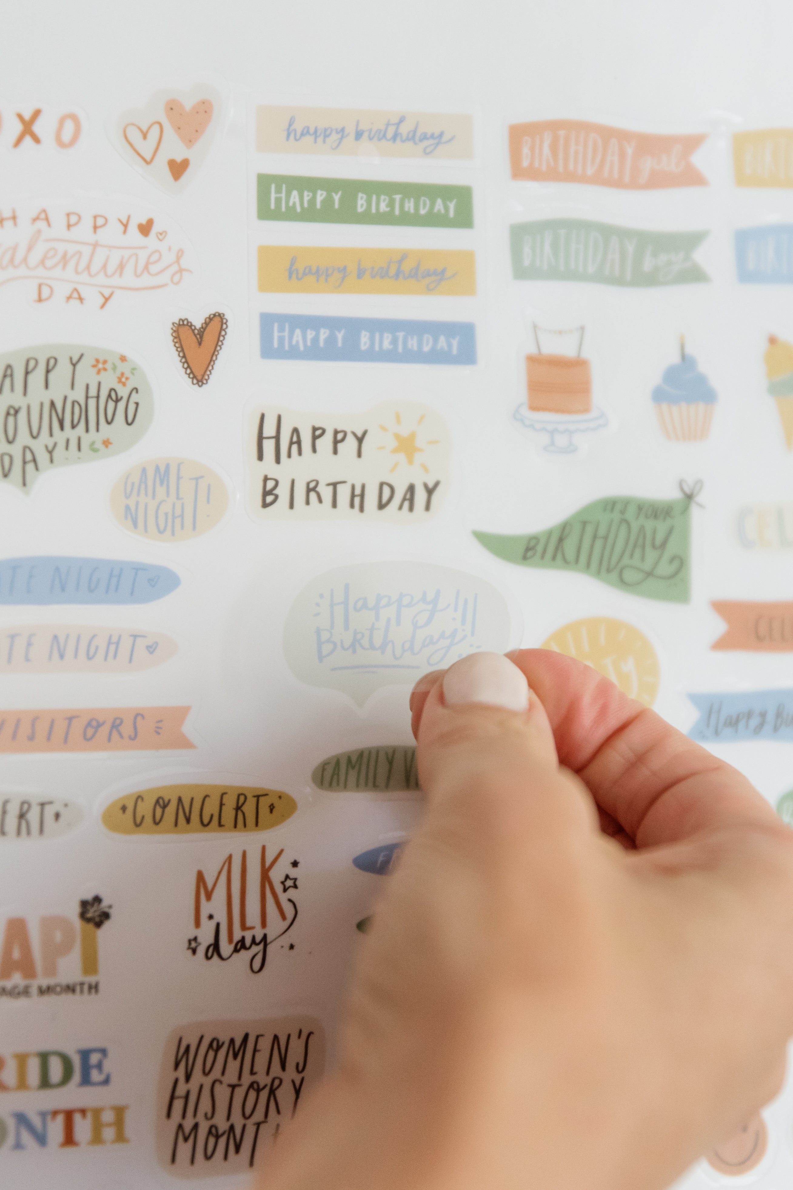 Hand peeling a happy birthday sticker from the family calendar sticker sheet