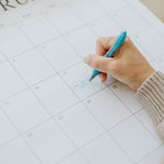 Hand writing plans on a month in the 2027 family wall calendar
