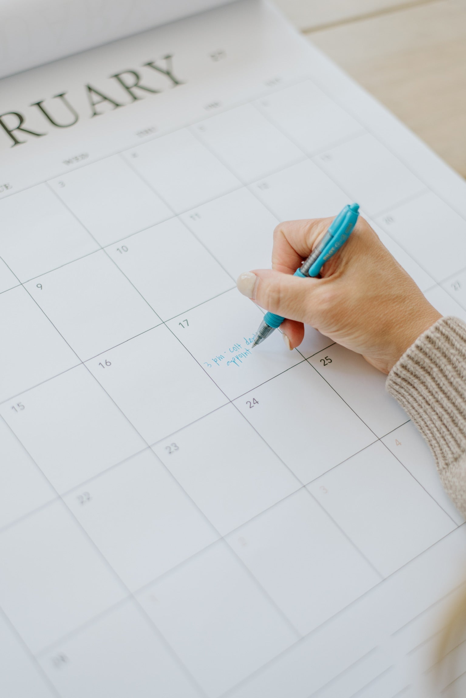 Hand writing plans on a month in the 2027 family wall calendar