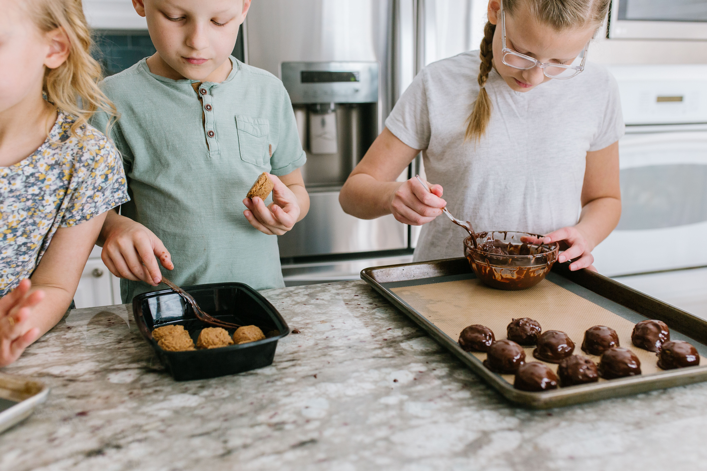 Kids dipping peanut butter balls into chocolate