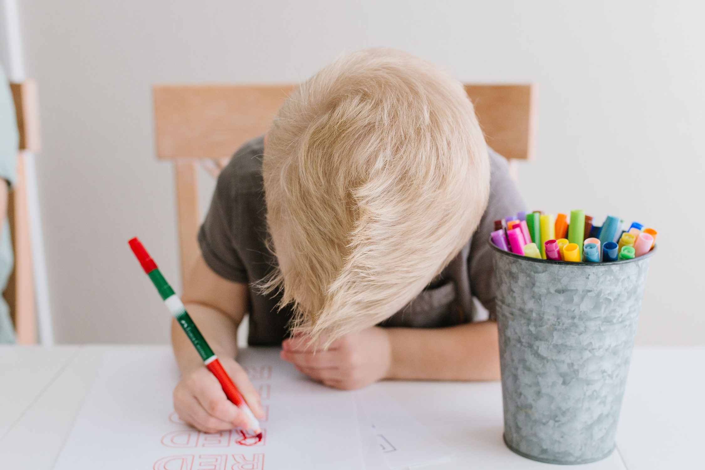 Boy coloring on paper sitting at a table