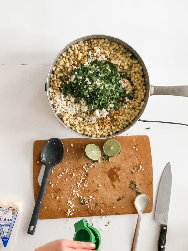 A pan of corn with lime, cilantro, and cheese added in