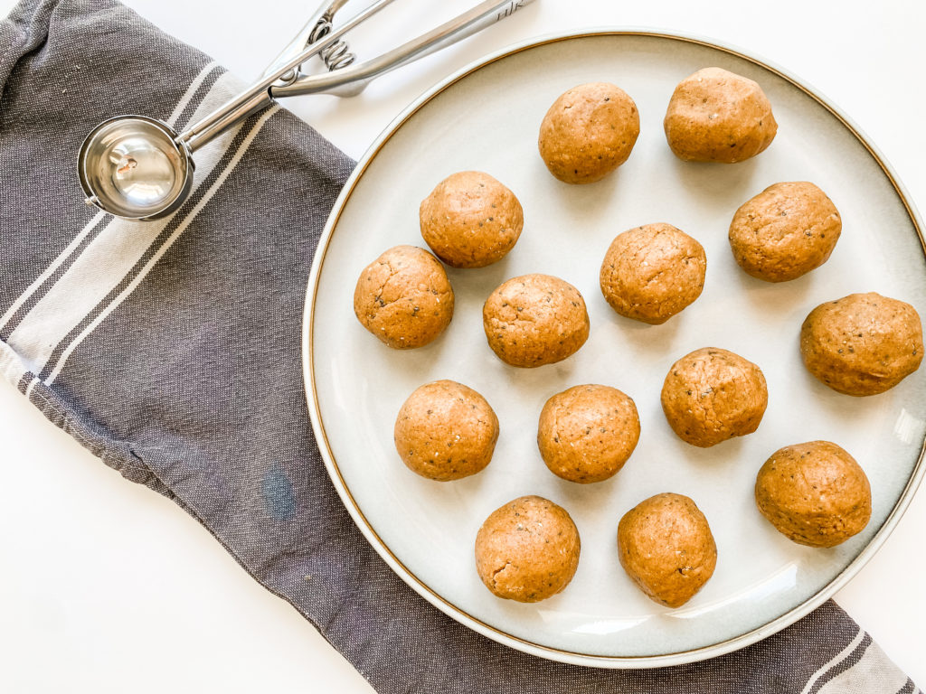 Almond butter protein balls on a plate with a food scoop next to it