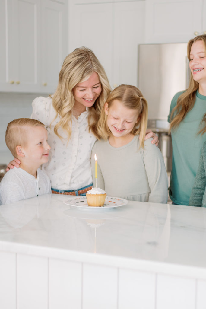 Family gathered around the Home & Kind birthday plate with a cupcake on it