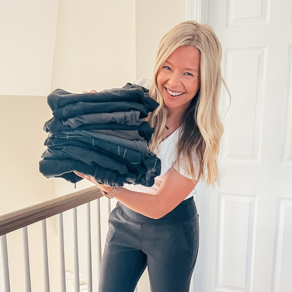 Brittney holding a stack of folded joggers